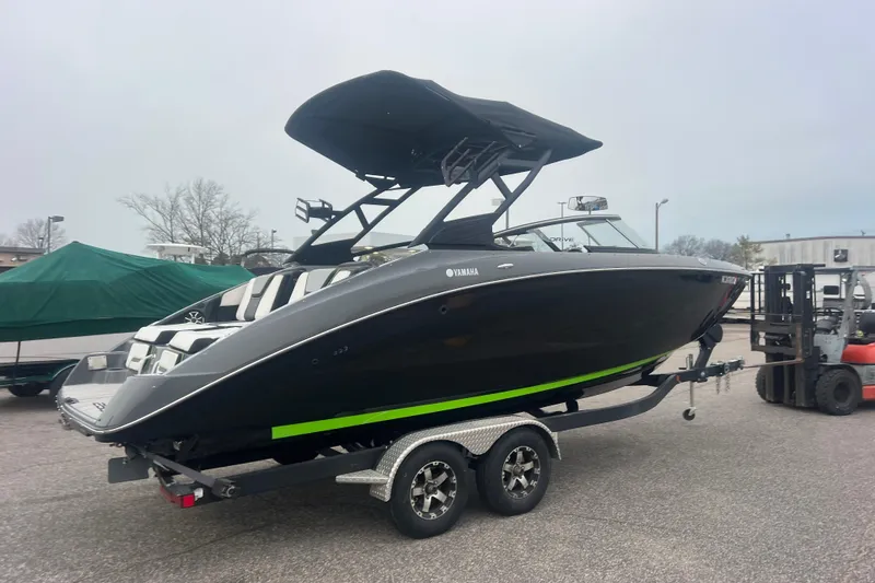 Slide: The Image of 2021 Yamaha Boats 255XD on trailer, sleek black design with green accents, parked outdoors. - 3