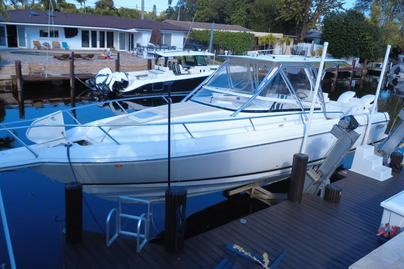 Slide: The Image of 2005 Intrepid 348 Walkaround boat docked at a marina, surrounded by calm water. - 11
