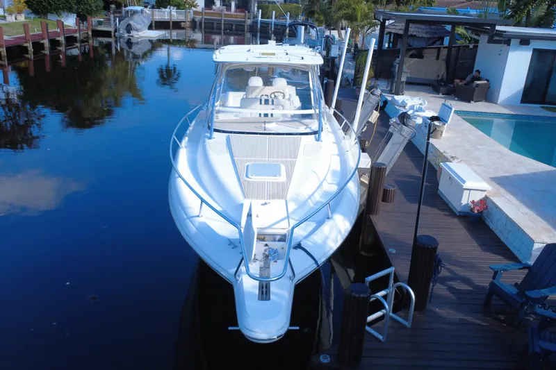 Slide: The Image of 2005 Intrepid 348 Walkaround boat docked by a poolside in a serene setting. - 13