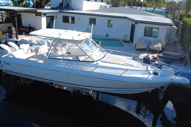 Slide: The Image of 2005 Intrepid 348 Walkaround boat docked near modern house with pool. - 2