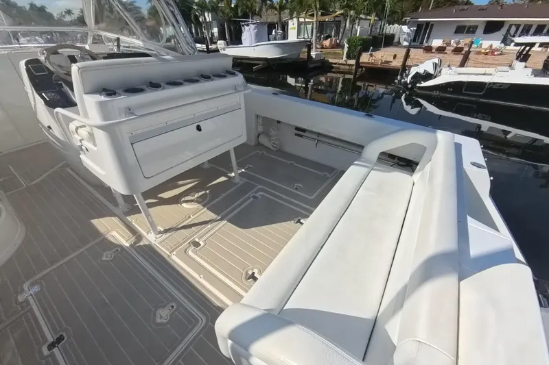 Slide: The Image of 2005 Intrepid 348 Walkaround boat interior with seating and storage, docked by waterfront homes. - 24