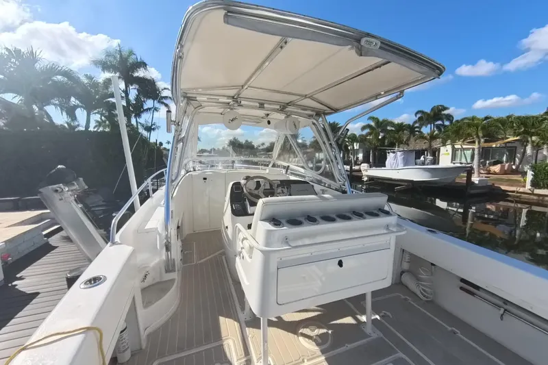Slide: The Image of 2005 Intrepid 348 Walkaround boat docked, featuring spacious deck and helm under clear blue sky. - 27