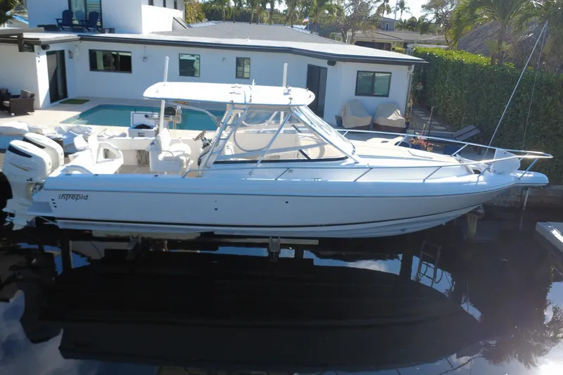 Slide: The Image of 2005 Intrepid 348 Walkaround boat docked near modern waterfront home. - 4