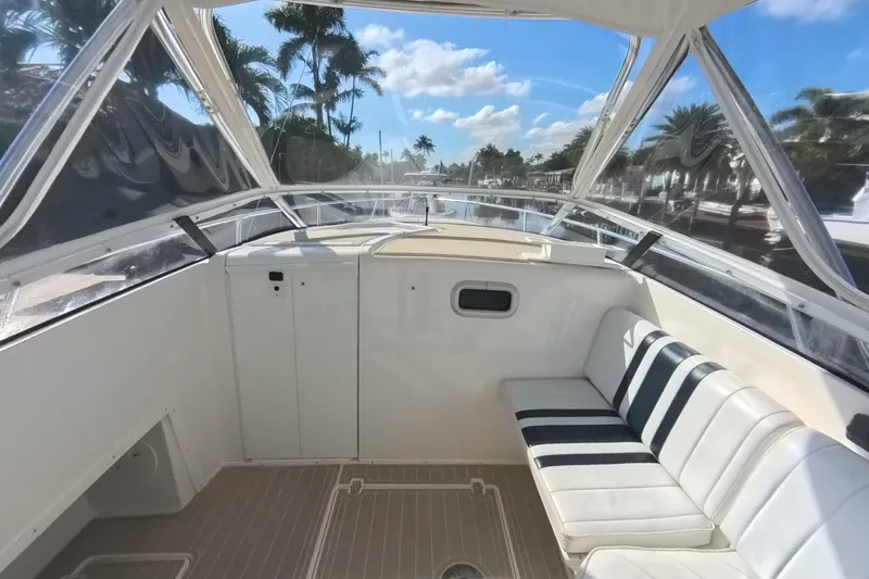 Slide: The Image of 2005 Intrepid 348 Walkaround boat interior with seating, clear skies, and palm trees. - 46