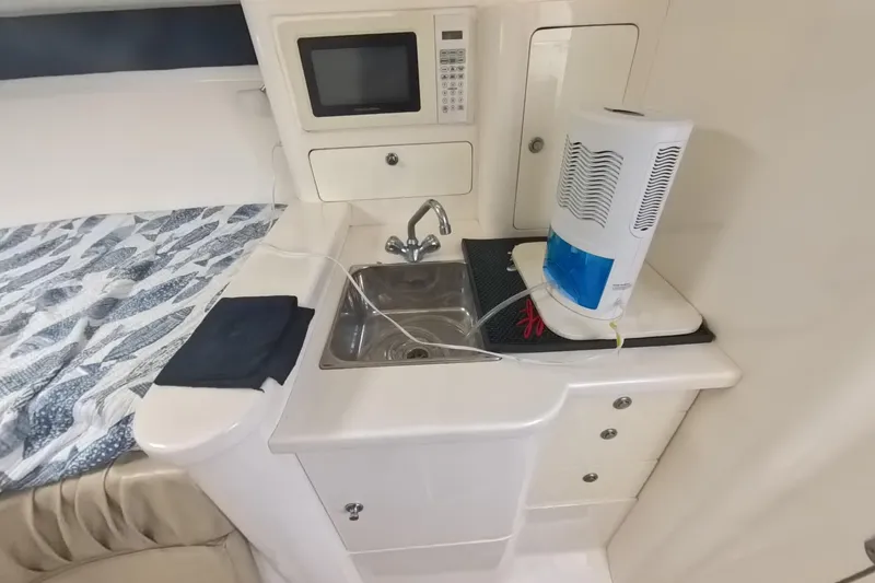 Slide: The Image of 2005 Intrepid 348 Walkaround interior with kitchenette, sink, microwave, and bed. - 58