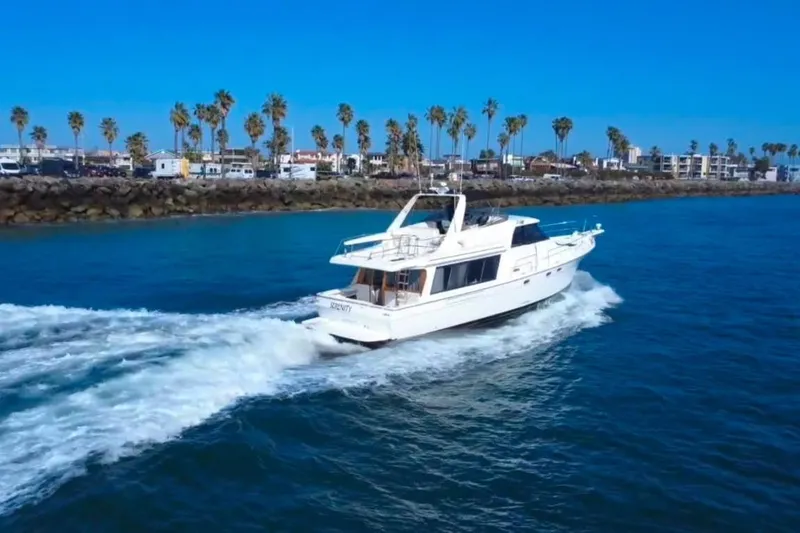 Slide: The Image of Bayliner 4788 Pilot House Motoryacht 1994 cruising on blue ocean near palm-lined shore. - 3