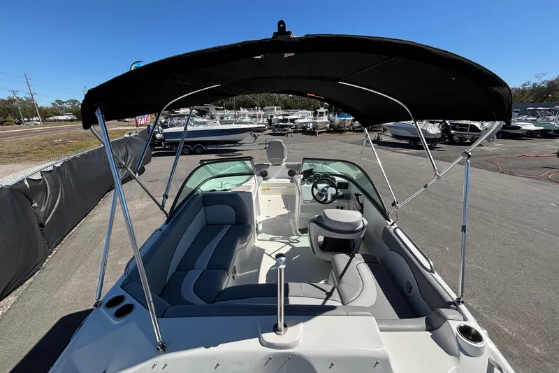 Slide: The Image of 2021 NauticStar 203 DC boat with canopy, parked in a marina under clear blue sky. - 13