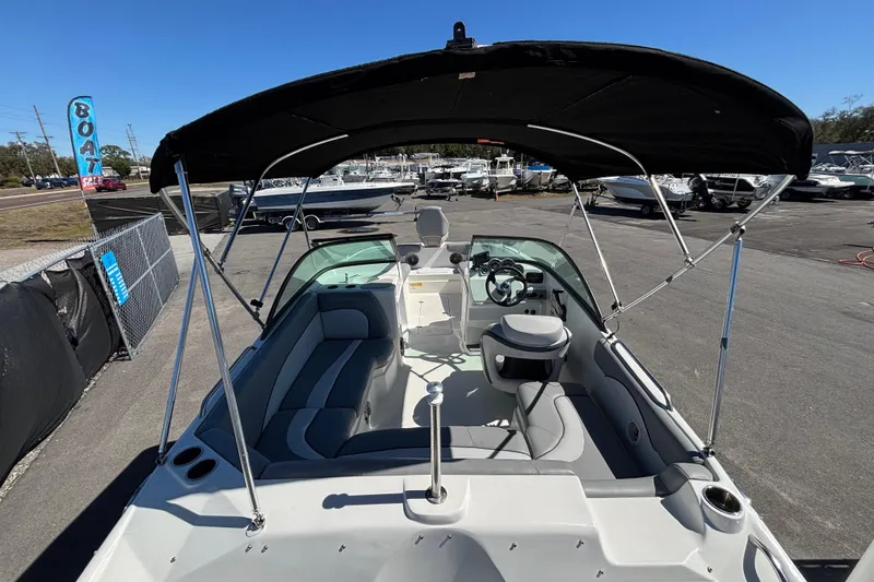 Slide: The Image of 2021 NauticStar 203 DC boat with canopy, parked in a marina under clear blue sky. - 14