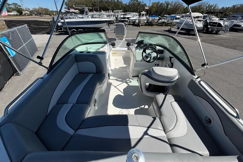 Slide: The Image of 2021 NauticStar 203 DC boat interior with seating and steering wheel, docked at marina. - 17