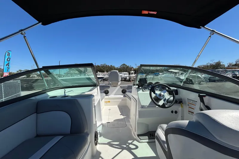 Slide: The Image of 2021 NauticStar 203 DC boat interior with steering wheel and seating under canopy. - 19