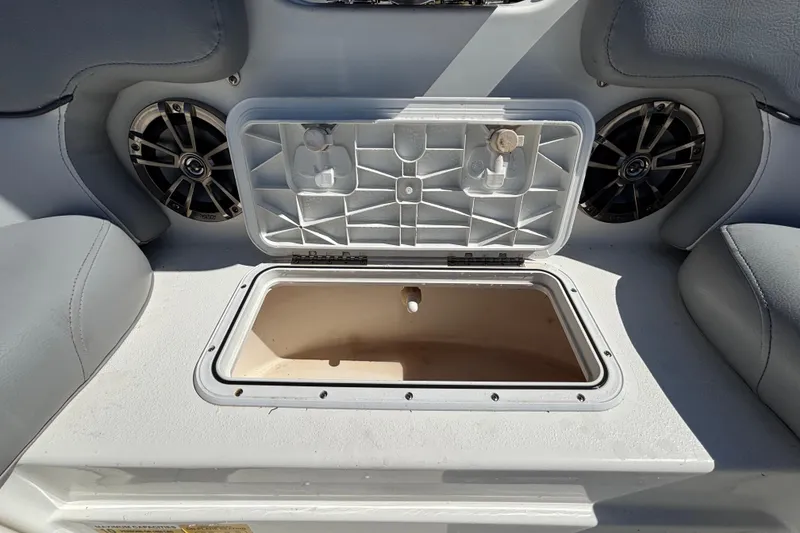 Slide: The Image of 2021 NauticStar 203 DC boat storage compartment with open lid and speakers. - 37