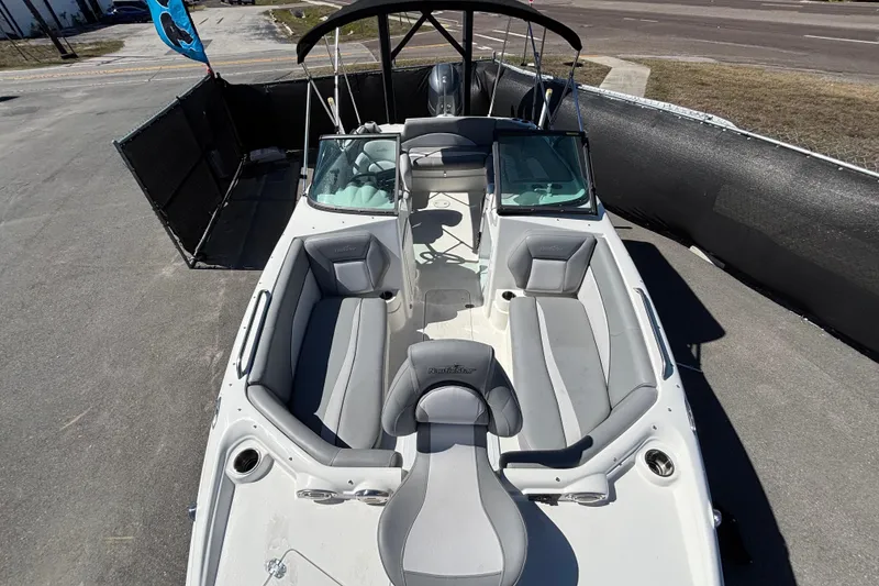 Slide: The Image of 2021 NauticStar 203 DC boat with gray seating and black canopy, parked on pavement. - 42