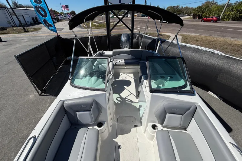 Slide: The Image of 2021 NauticStar 203 DC boat with seating, windshield, and canopy in a parking area. - 44