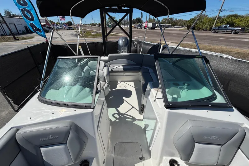 Slide: The Image of 2021 NauticStar 203 DC boat interior with seating and windshield, parked outdoors. - 45