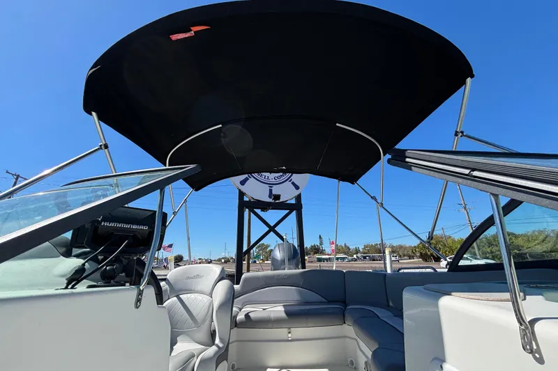 Slide: The Image of 2021 NauticStar 203 DC boat interior with seating and canopy under clear blue sky. - 48