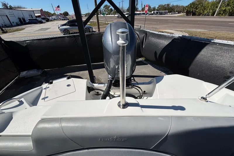 Slide: The Image of 2021 NauticStar 203 DC boat with outboard motor, parked outdoors. - 60