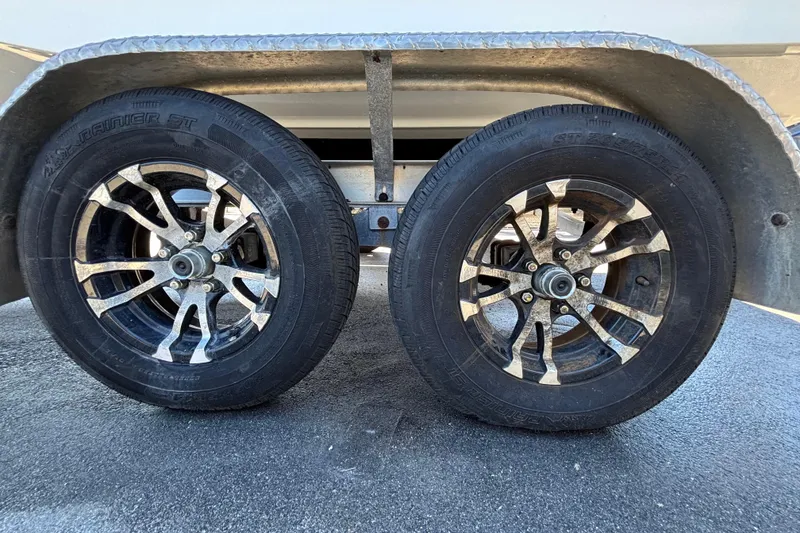 Slide: The Image of Trailer wheels of a 2021 NauticStar 203 DC boat on pavement. - 68