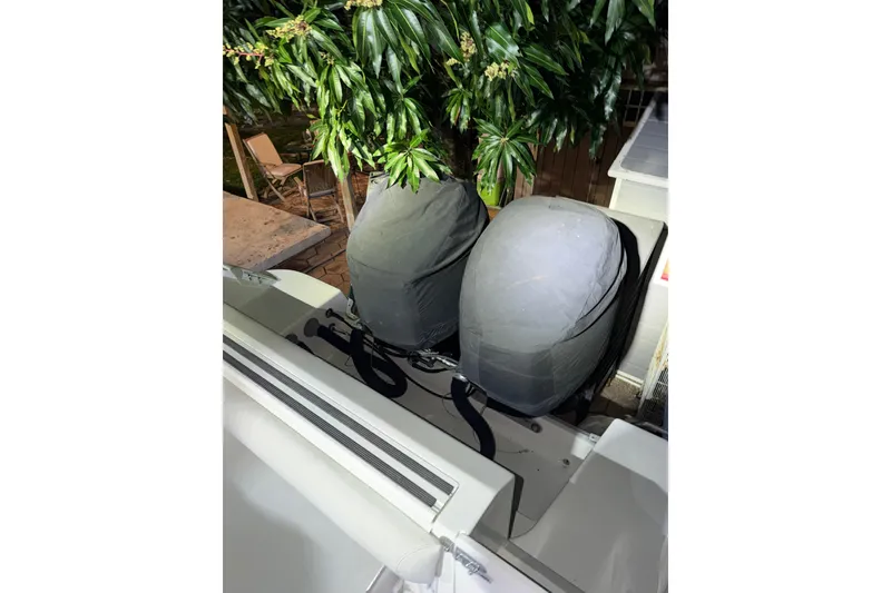 Slide: The Image of Covered outboard motors on a 2001 Wellcraft 270 Coastal boat, surrounded by greenery. - 17