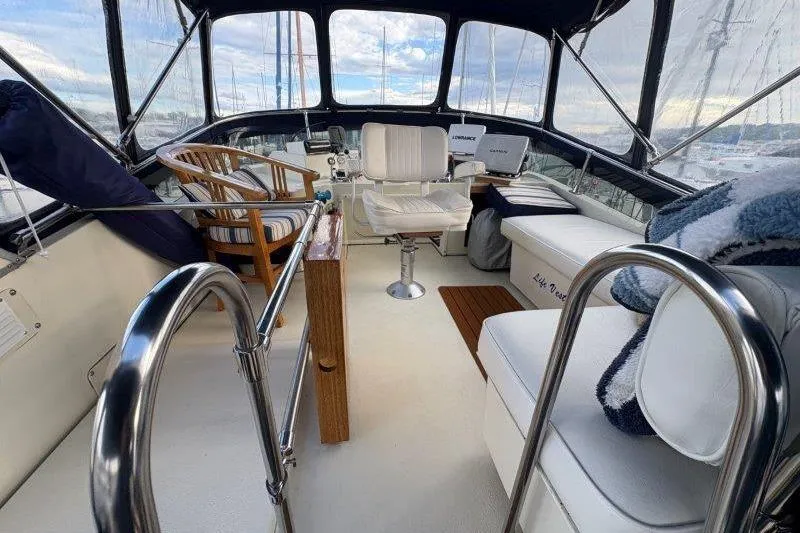 Slide: The Image of 1987 Tollycraft 34 Sundeck Motor Yacht interior with marina view, featuring a striped chair. - 13
