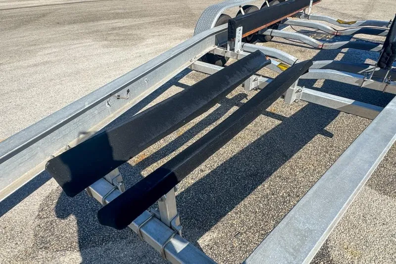 Slide: The Image of 2021 Wellcraft 262 Fisherman boat trailer with dual axles on a paved surface. - 100