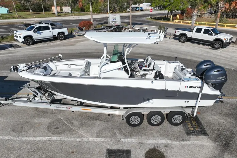 Slide: The Image of 2021 Wellcraft 262 Fisherman boat on trailer, parked in a lot with trucks nearby. - 3