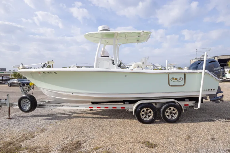 Slide: The Image of 2016 Sea Hunt Gamefish 25 boat on trailer, parked outdoors under a cloudy sky. - 8