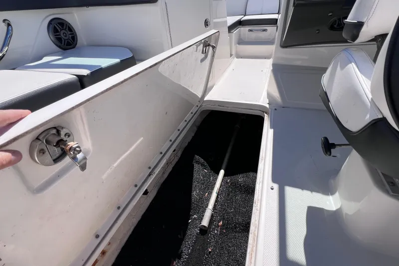 Slide: The Image of 2015 Sea Ray 21 SPX OB boat interior storage compartment open, revealing black carpeted space. - 38
