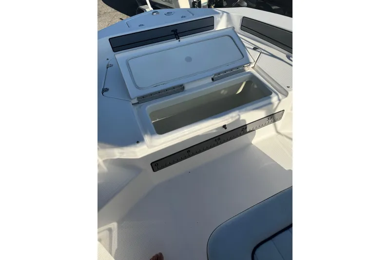 Slide: The Image of Open storage compartment on 2018 Yamaha Boats 190 FSH Deluxe, featuring a built-in measuring ruler. - 20