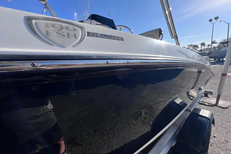 Slide: The Image of 2018 Yamaha Boats 190 FSH Deluxe on trailer, side view under clear blue sky. - 5
