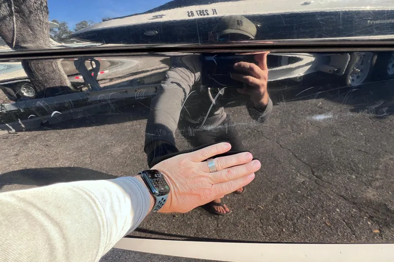 Slide: The Image of Hand touching 2018 Yamaha Boats 190 FSH Deluxe hull, reflecting surroundings. - 9