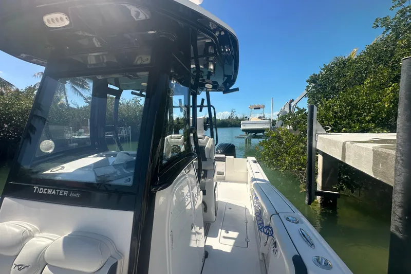 Slide: The Image of 2021 Tidewater 292 CC Adventure boat docked near lush greenery and clear blue water. - 3