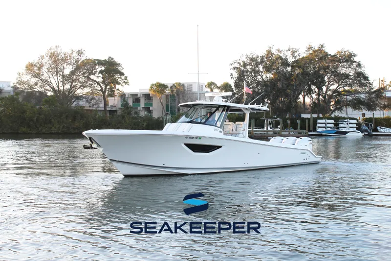 Slide: The Image of 2023 Pursuit S 378 Sport boat on calm water with trees in background. - 0