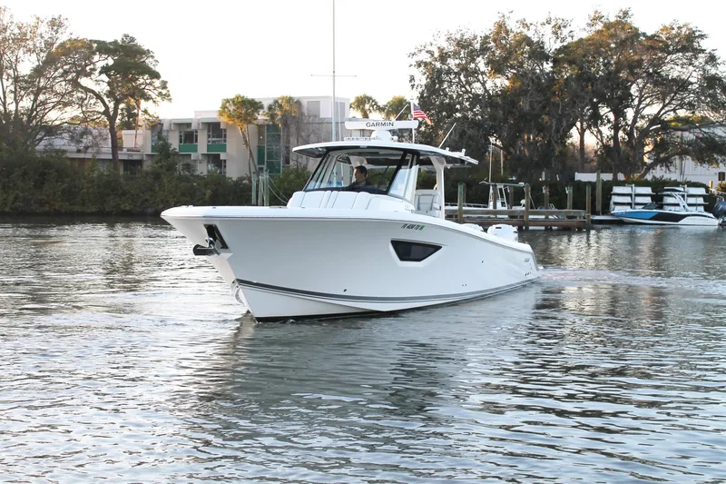Slide: The Image of 2023 Pursuit S 378 Sport boat cruising on a calm waterway near a marina. - 13