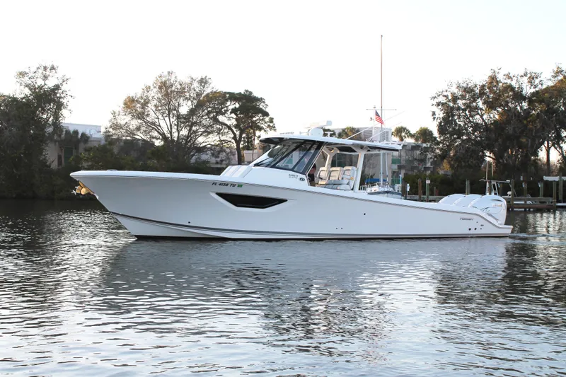 Slide: The Image of 2023 Pursuit S 378 Sport boat cruising on calm water, surrounded by trees. - 2