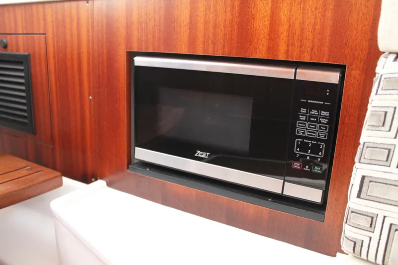Slide: The Image of Built-in microwave in 2023 Pursuit S 378 Sport boat interior, featuring wood paneling. - 61