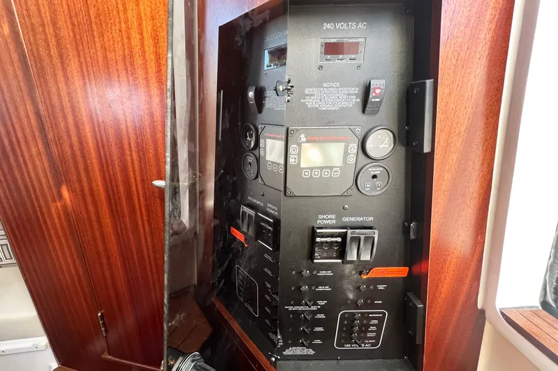 Slide: The Image of Electrical control panel on 2023 Pursuit S 378 Sport boat, featuring wood paneling. - 63