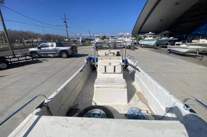 Slide: The Image of 2007 Carolina Skiff 1780 DLX boat parked outdoors, surrounded by vehicles and other boats. - 14