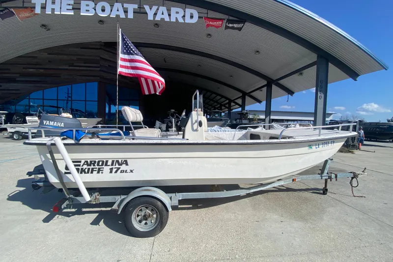 Slide: The Image of 2007 Carolina Skiff 1780 DLX boat on trailer at dealership, American flag displayed. - 3