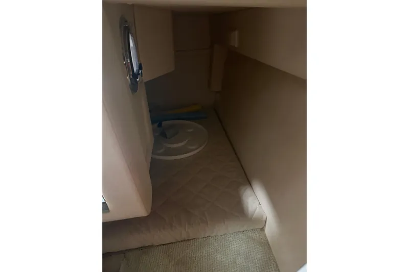 Slide: The Image of 2007 Sea Ray 240 Sundancer cabin interior with beige upholstery and porthole window. - 4