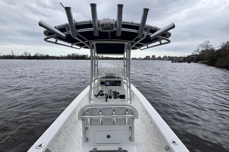 Slide: The Image of 2014 Riddick Bay Runner 2290 boat on a calm river under cloudy skies. - 10