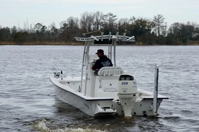 Slide: The Image of 2014 Riddick Bay Runner 2290 boat on a calm river with a person steering. - 4