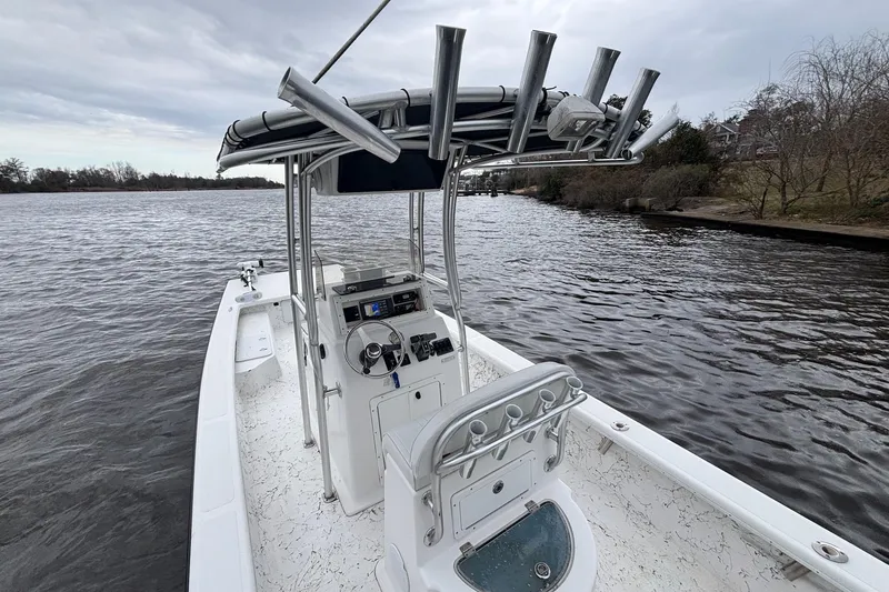 Slide: The Image of 2014 Riddick Bay Runner 2290 boat on calm water, featuring a central console and rod holders. - 9