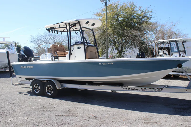 Slide: The Image of 2022 Sea Pro 248 Bay boat on trailer, blue hull, parked outdoors. - 3