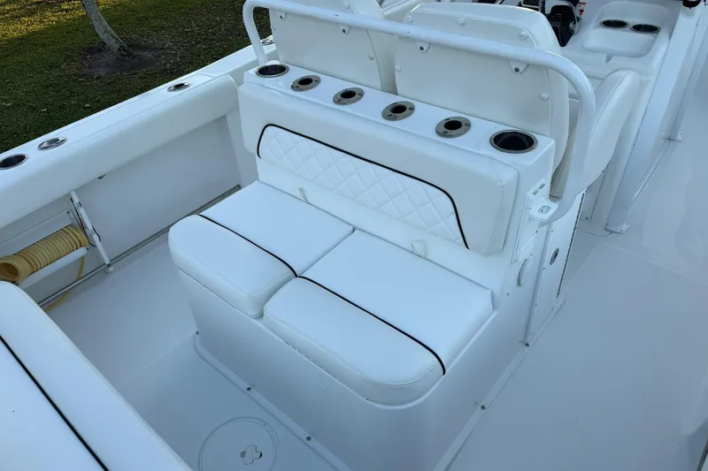 Slide: The Image of 2014 Sea Hunt Gamefish 27 boat interior with white cushioned seating and cup holders. - 13