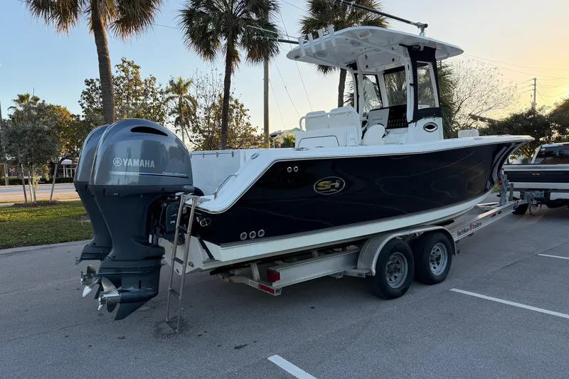 Slide: The Image of 2014 Sea Hunt Gamefish 27 boat on trailer with Yamaha engine, parked near palm trees. - 3