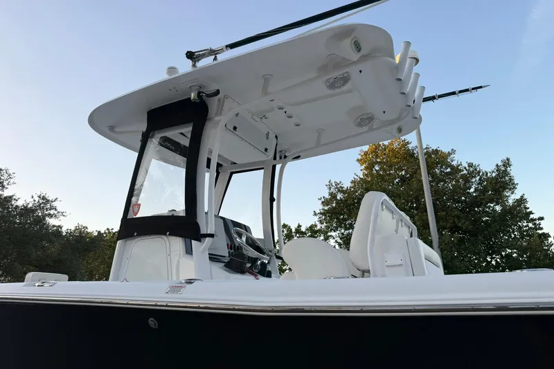 Slide: The Image of 2014 Sea Hunt Gamefish 27 boat with T-top and seating, against a clear sky backdrop. - 32