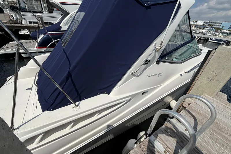 Slide: The Image of 2009 Sea Ray Sundancer 310 docked, featuring blue canopy and sleek white design. - 5
