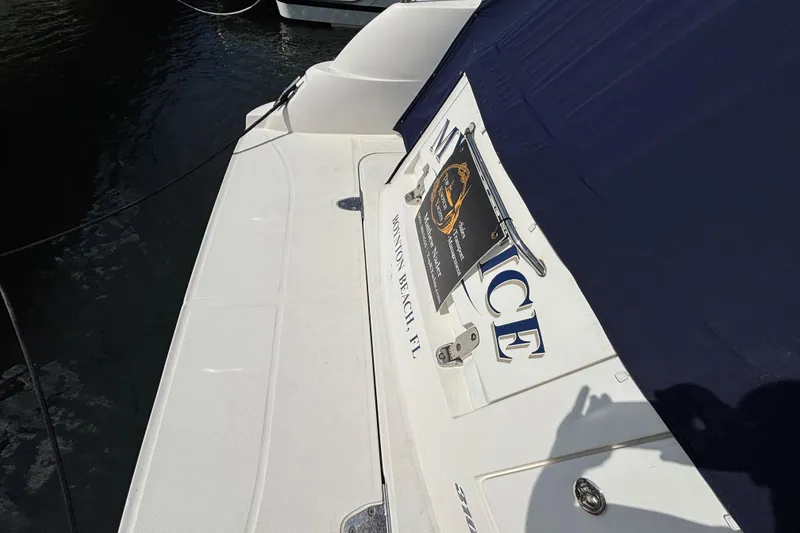 Slide: The Image of 2009 Sea Ray Sundancer 310 boat docked, featuring a white deck and navy cover. - 8