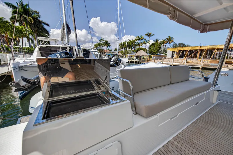Slide: The Image of 2022 Fountaine Pajot Tanna 47 yacht with outdoor seating and grill, docked by palm trees. - 20
