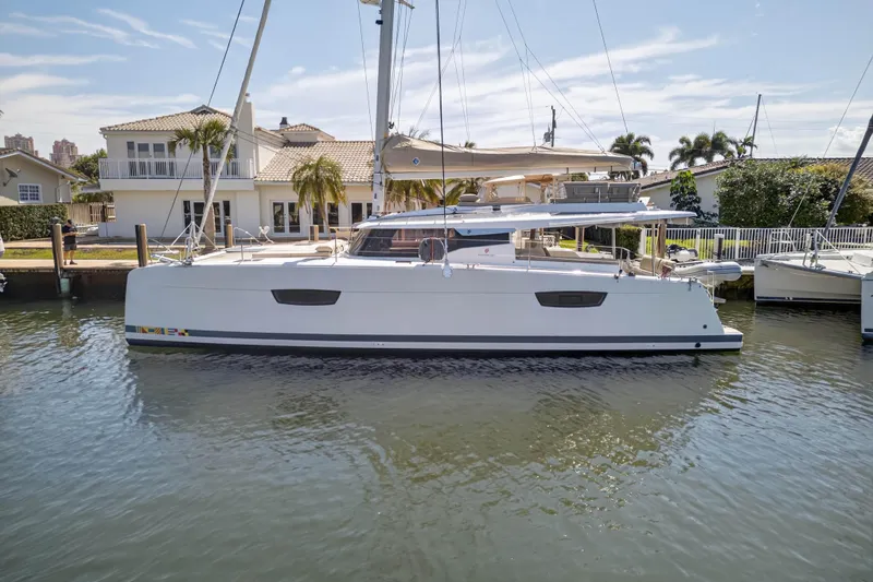 Slide: The Image of 2022 Fountaine Pajot Tanna 47 catamaran docked by waterfront homes. - 3